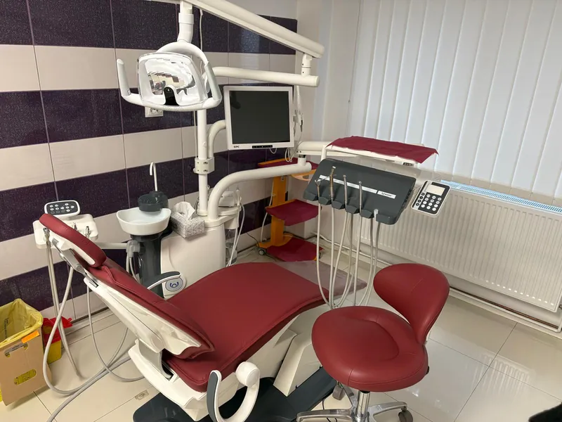 Unitul dentar din cabinetul Vera Med, cu scaun de culoare vișinie, lampă și monitor