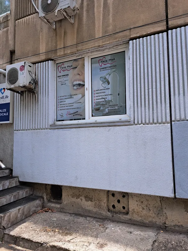 Intrarea cabinetului Vera Med de pe Strada Moinești 2, la parterul unui bloc, cu afișele Vera Med în geam